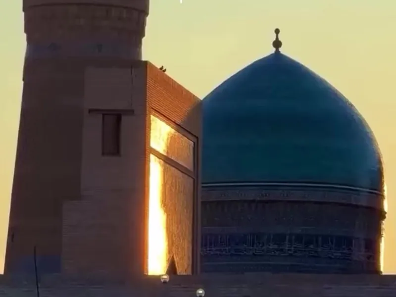 The Kalon minaret and a blue dome in Bukhara at sunset