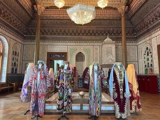 Silk ikat robes in a hall with carved plaster and painted ceilings