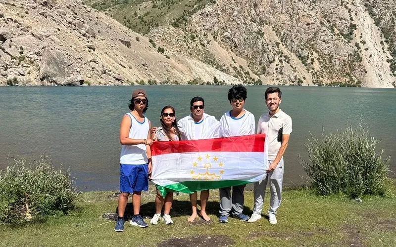 Our guide with guests holding the flag of Tajikistan at one of the Seven Lakes